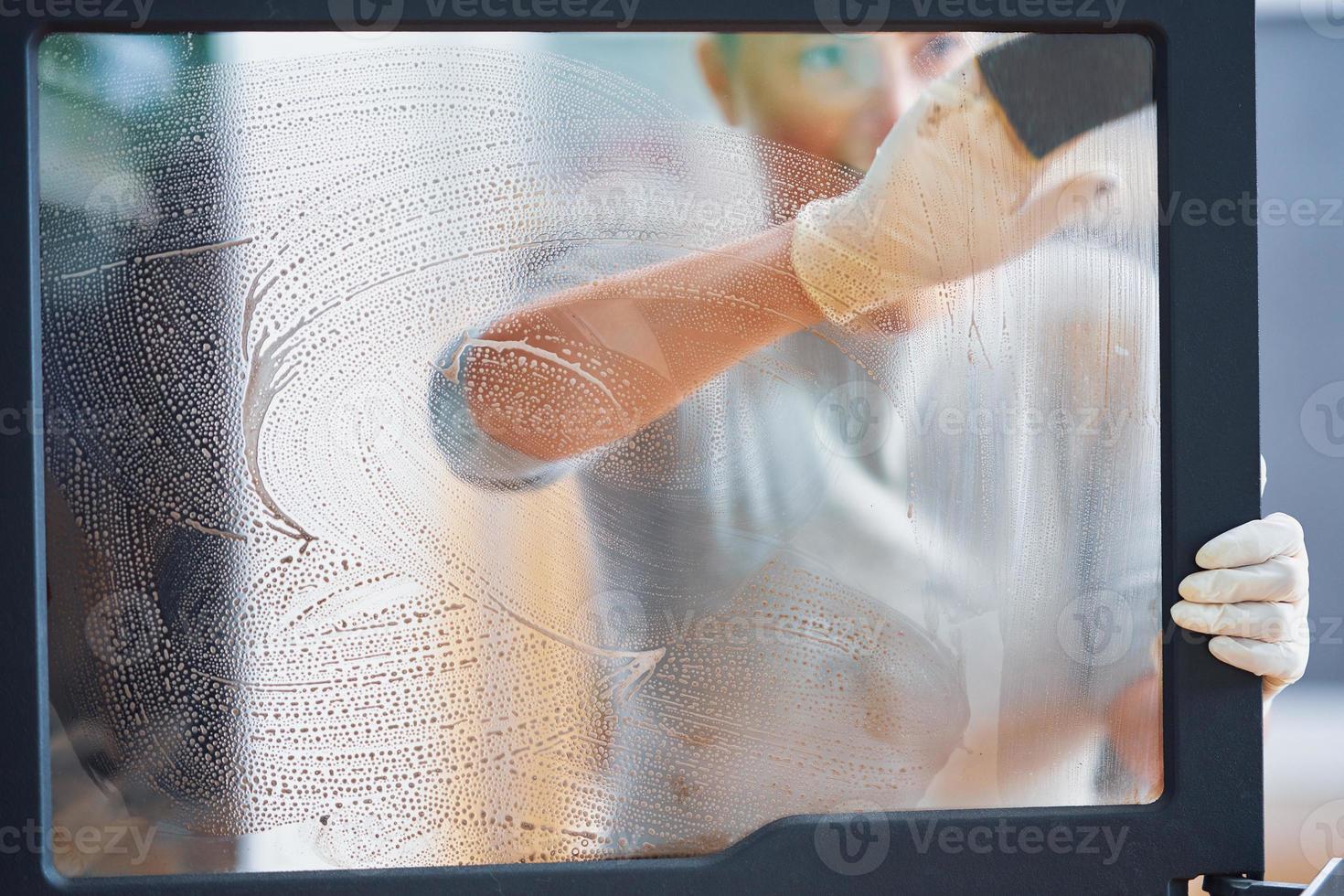 Picture of young woman cleaning fireplace glass doors photo