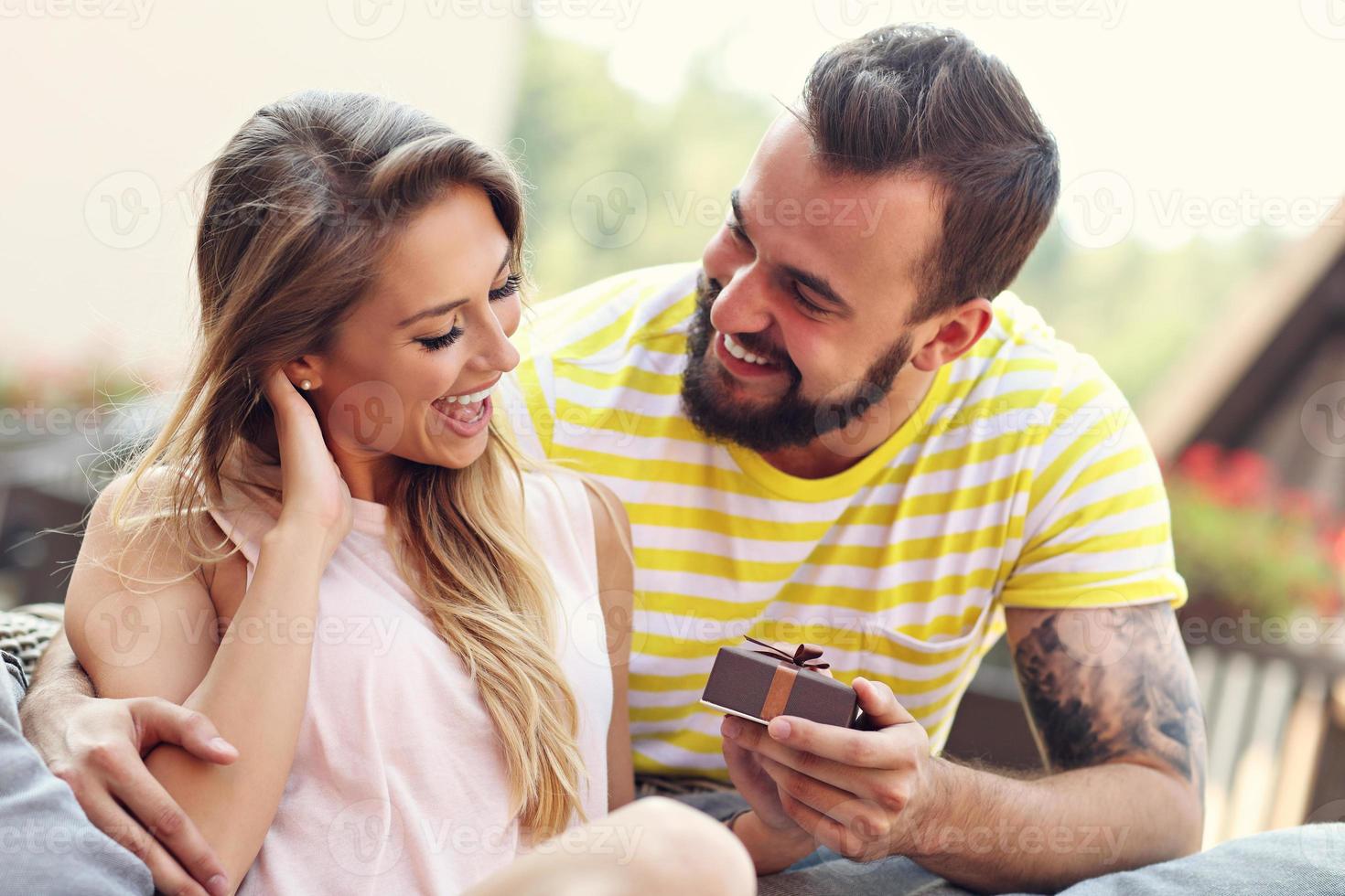 pareja feliz con presente sentado afuera foto