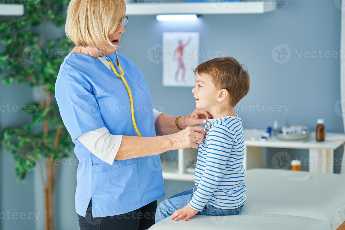 Pediatrician doctor examining little kids in clinic photo