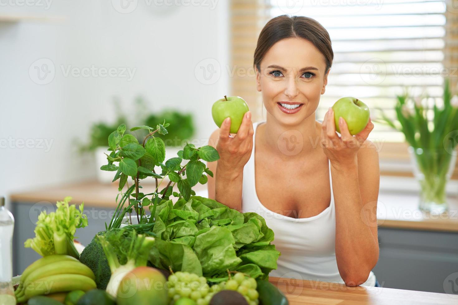 mujer adulta sana con comida verde en la cocina foto