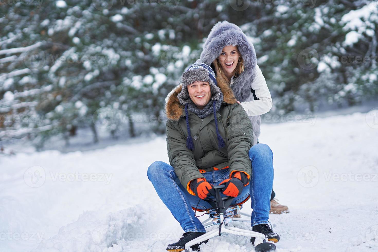 Couple having fun with sledge on snow in winter photo