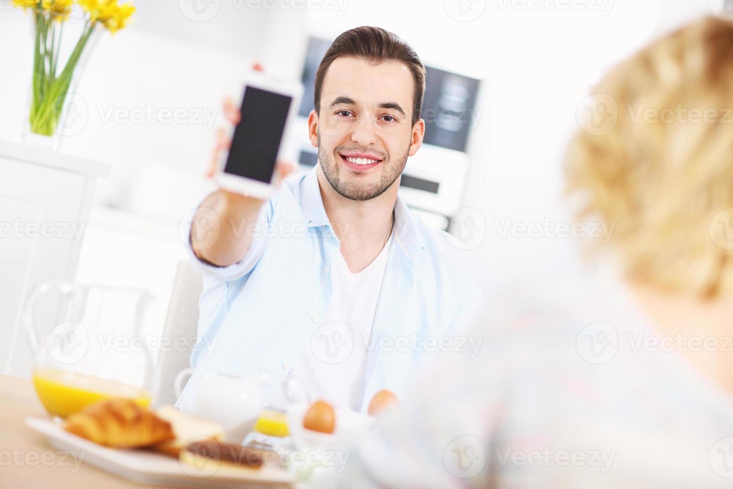 hombre feliz mostrando teléfono inteligente foto