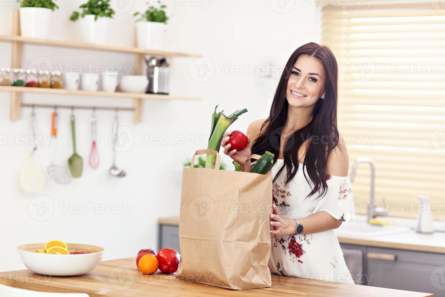 Portrait of smiling young housewife in modern kitchen photo