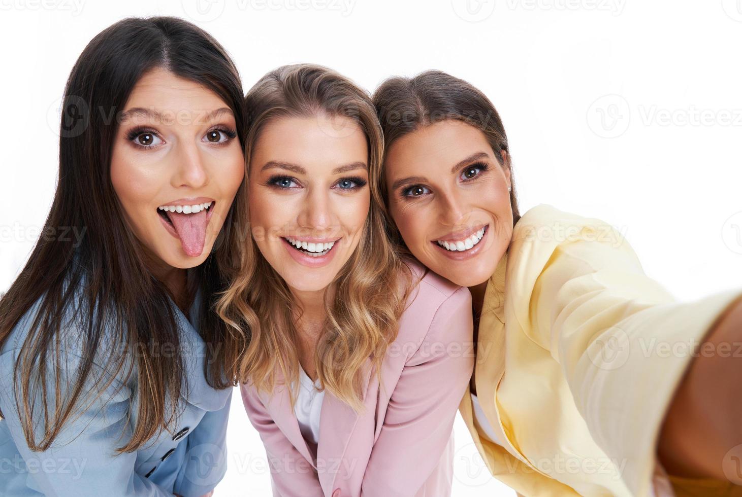 Three women in pastel suits posing over white background photo