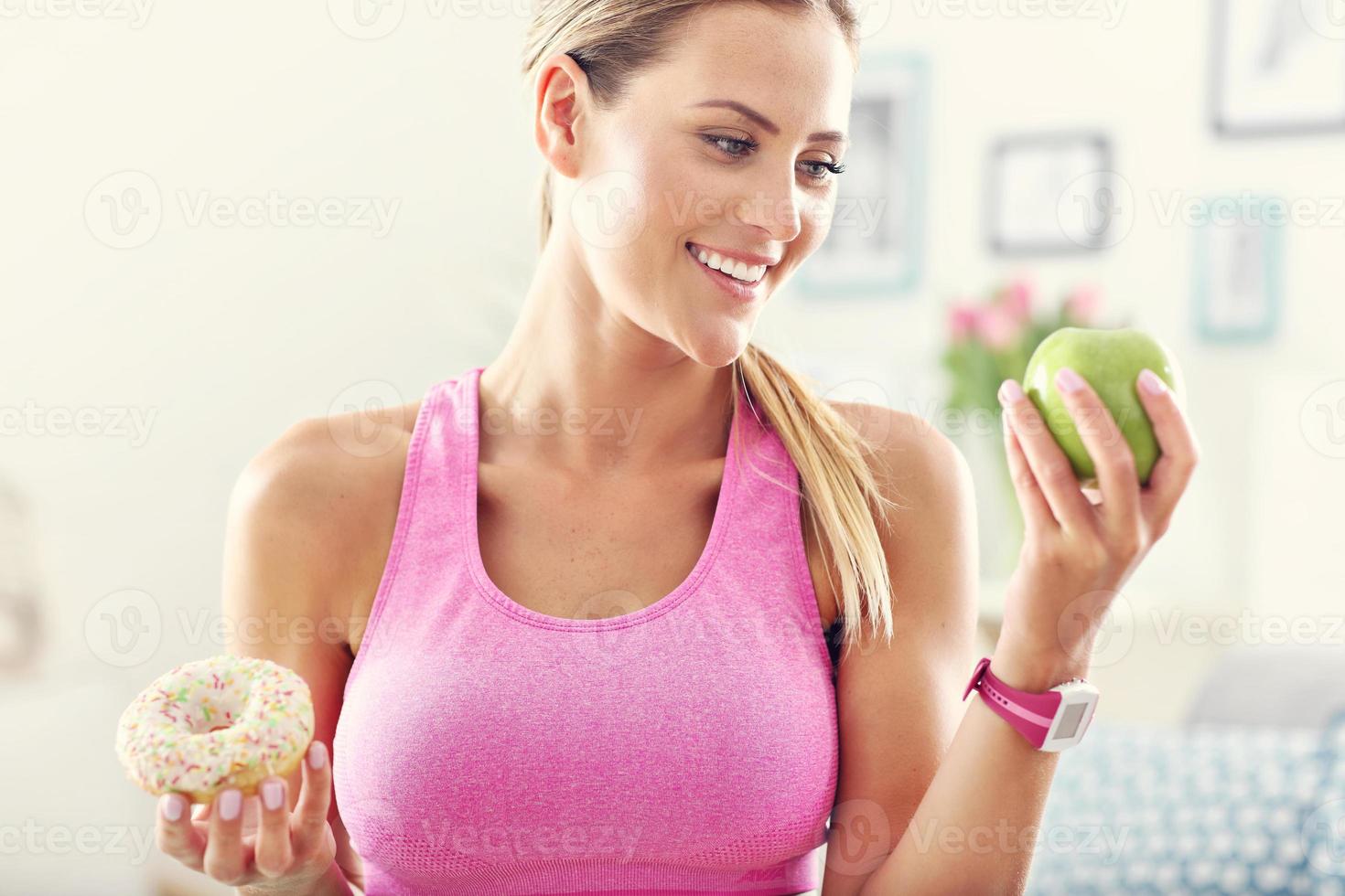 Sporty woman with apple and donut after workout photo