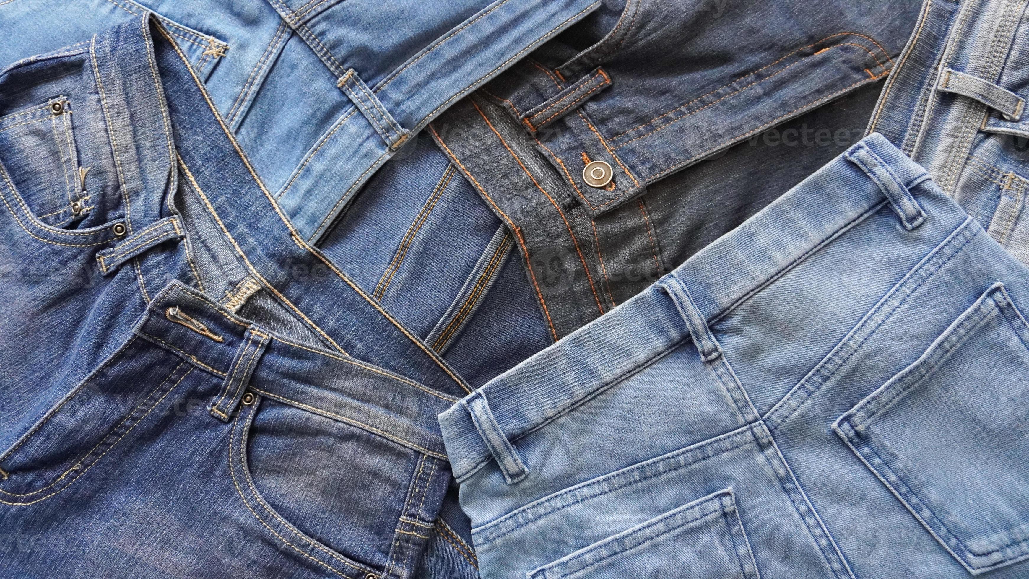 Stack of pairs of denim jeans of various blue shades and sizes 15812220