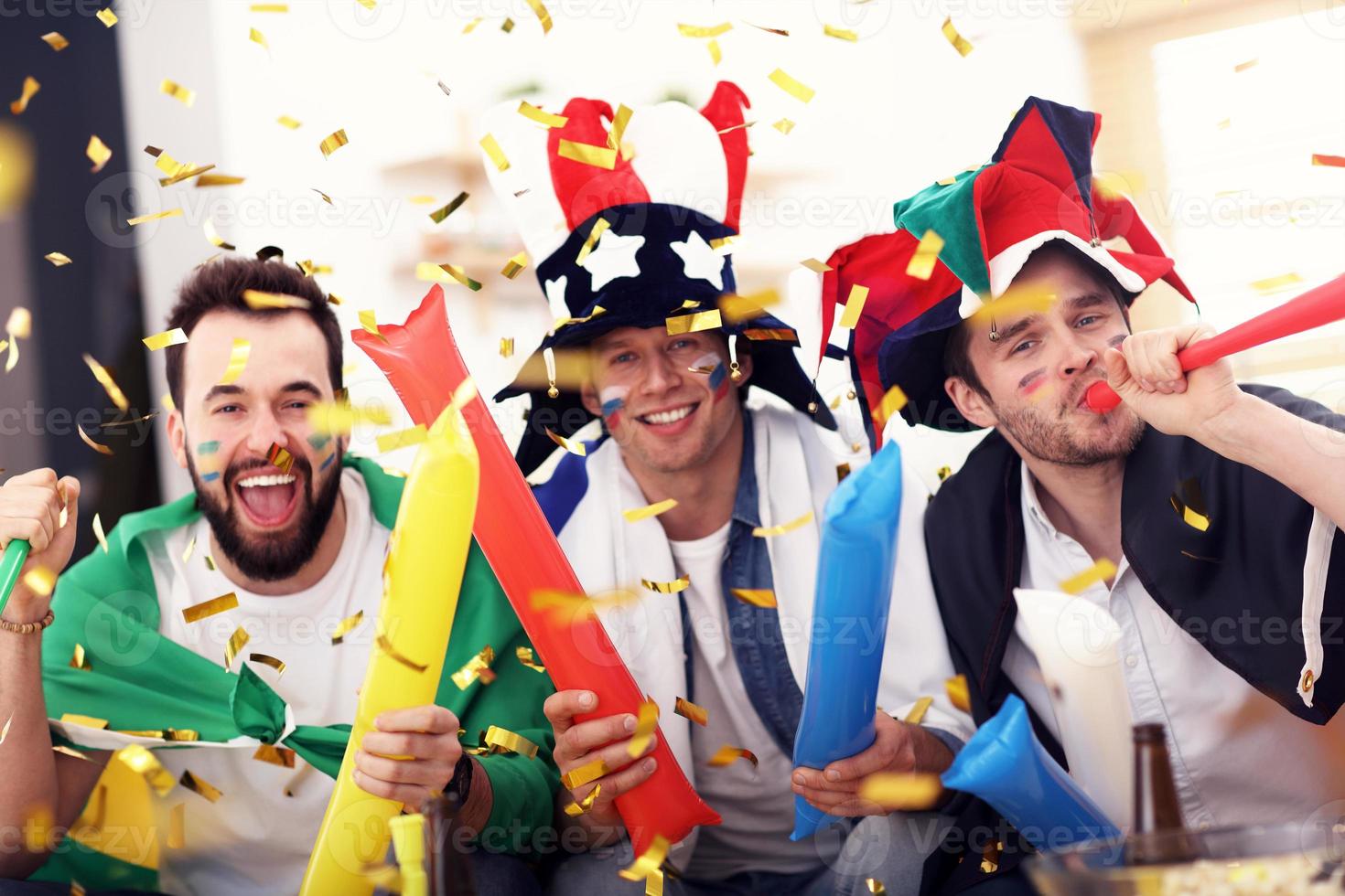 Happy male friends cheering and watching sports on tv photo