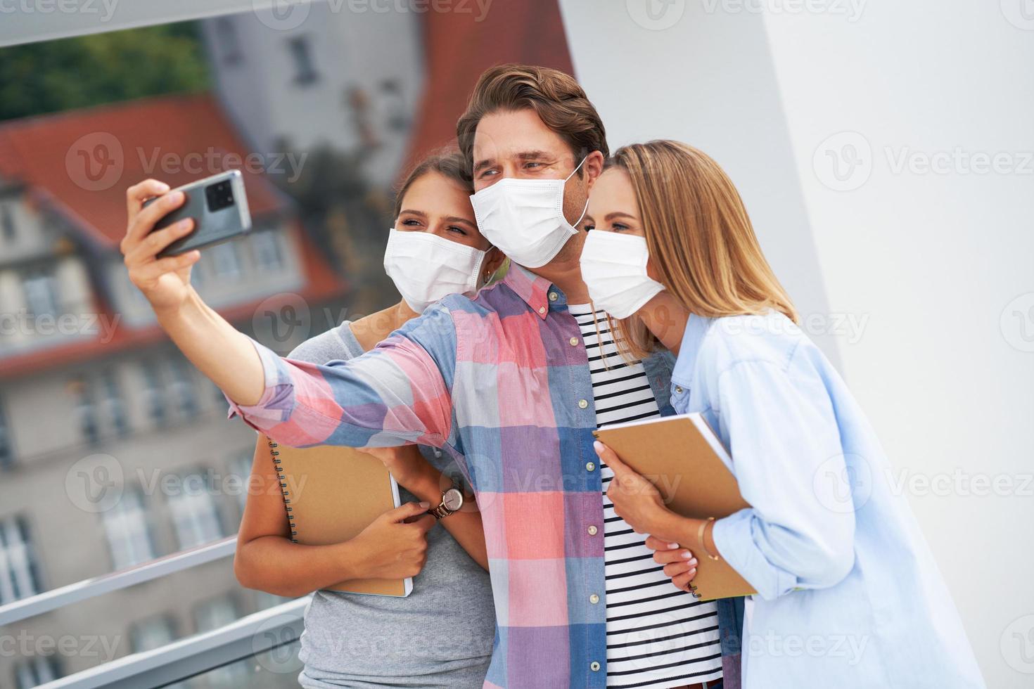 Couple of students wearing masks while taking selfie in the campus photo