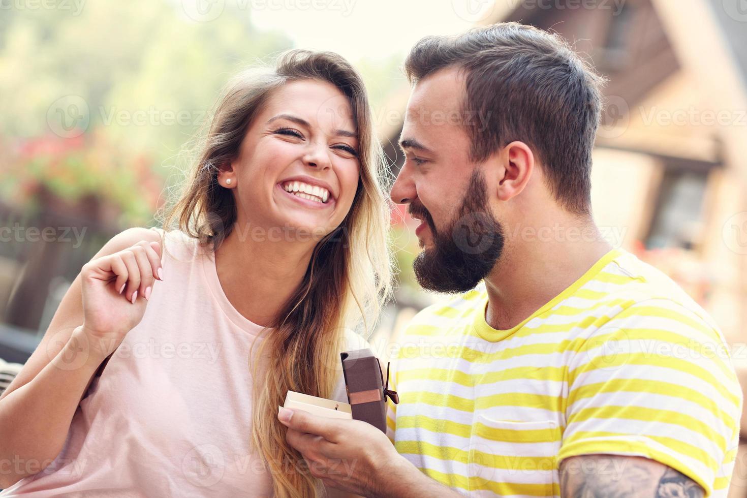 Young man proposing to beautiful woman outdoors photo