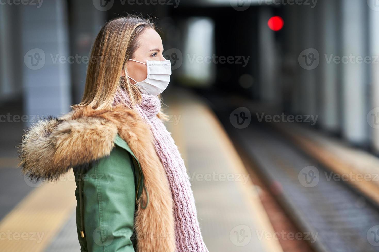 Adult woman at train station wearing masks due to covid-19 restrictions photo