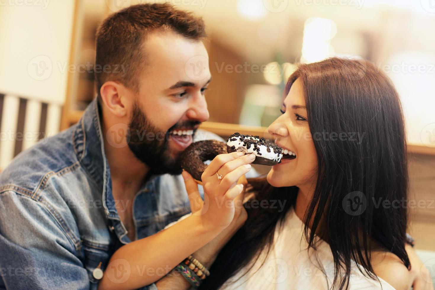 pareja romántica saliendo en un café y comiendo donas foto