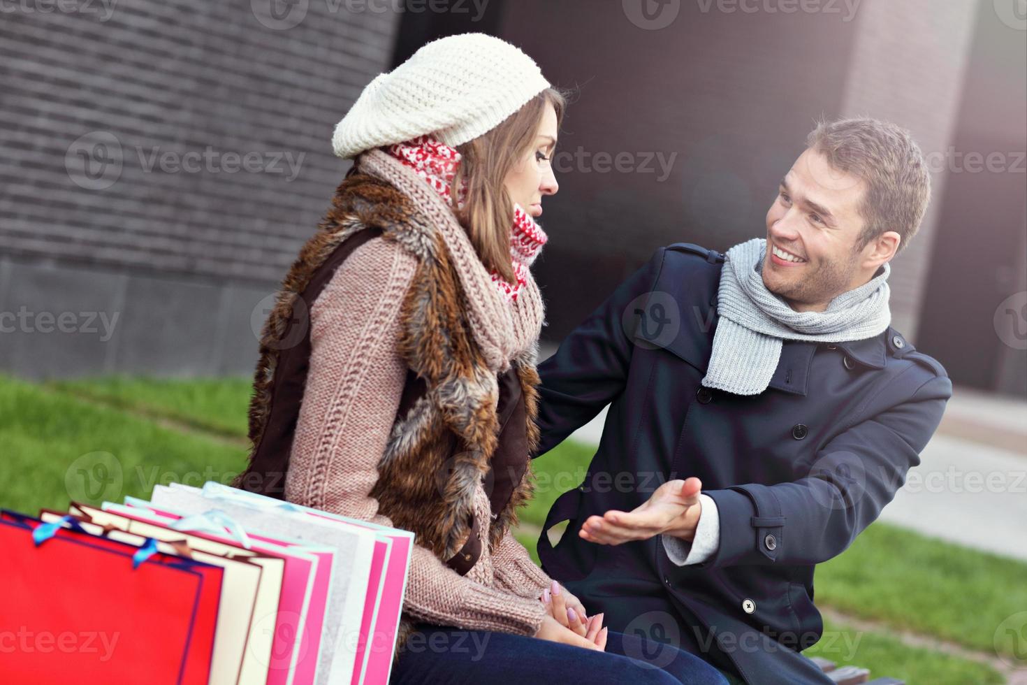 Young man showing disapproval to woman with many shopping bags photo