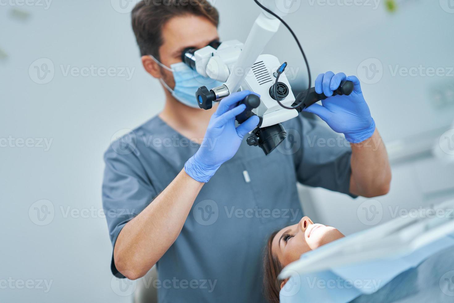 Dentist checking up patient teeth with microscope at surgery office photo