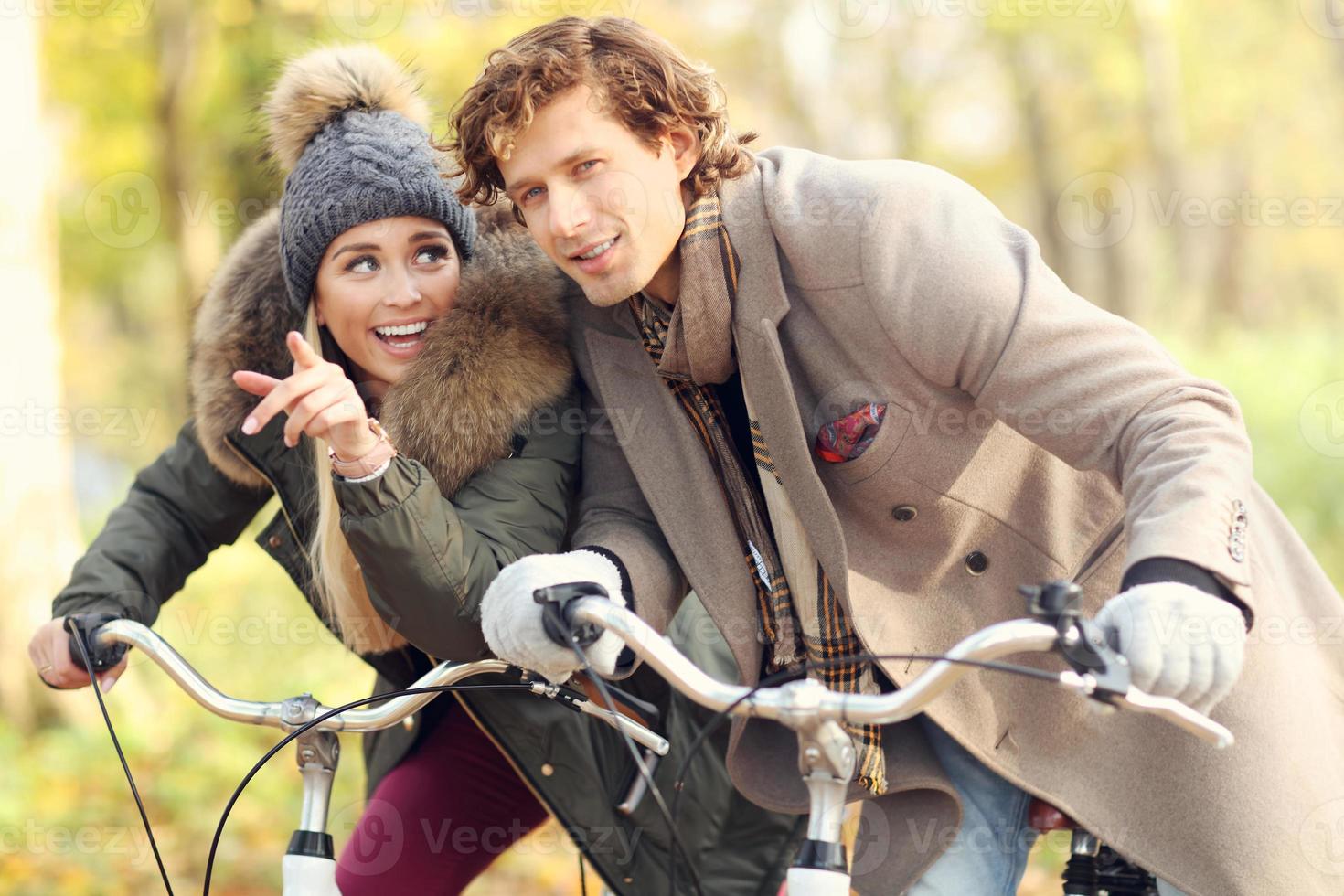 Happy couple on bikes in forest during fall time photo