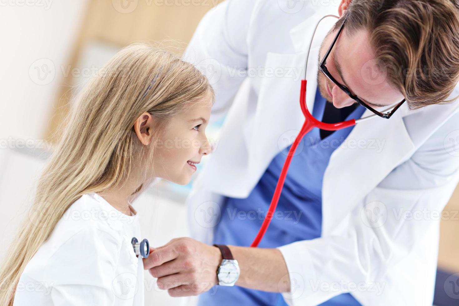 Little girl in clinic having a checkup with pediatrician photo