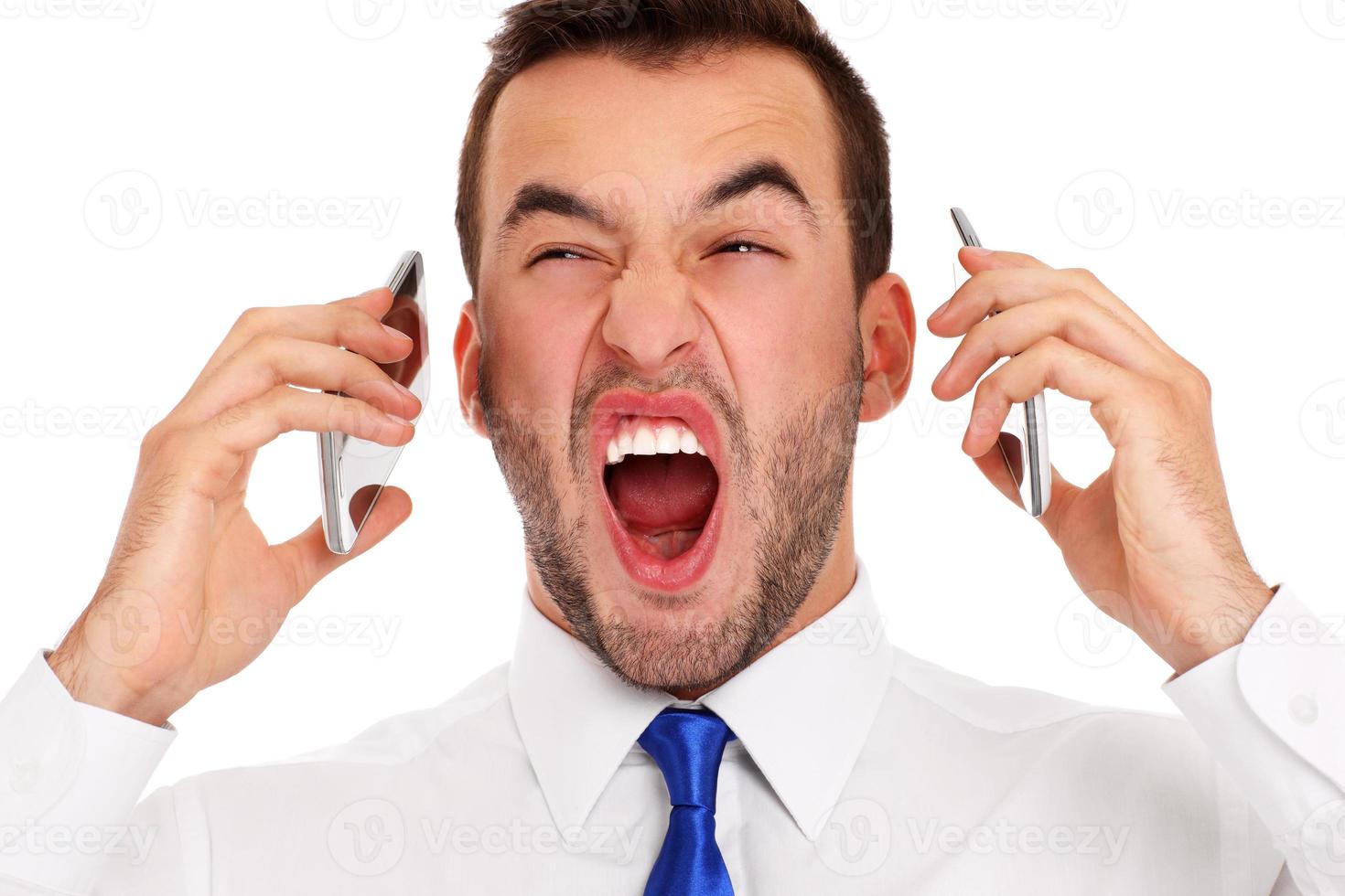 Angry businessman talking on two phones photo