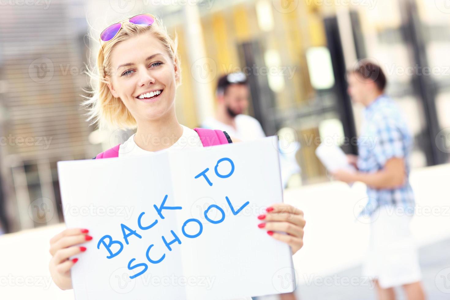 Young student standing in the campus with an open notebook photo