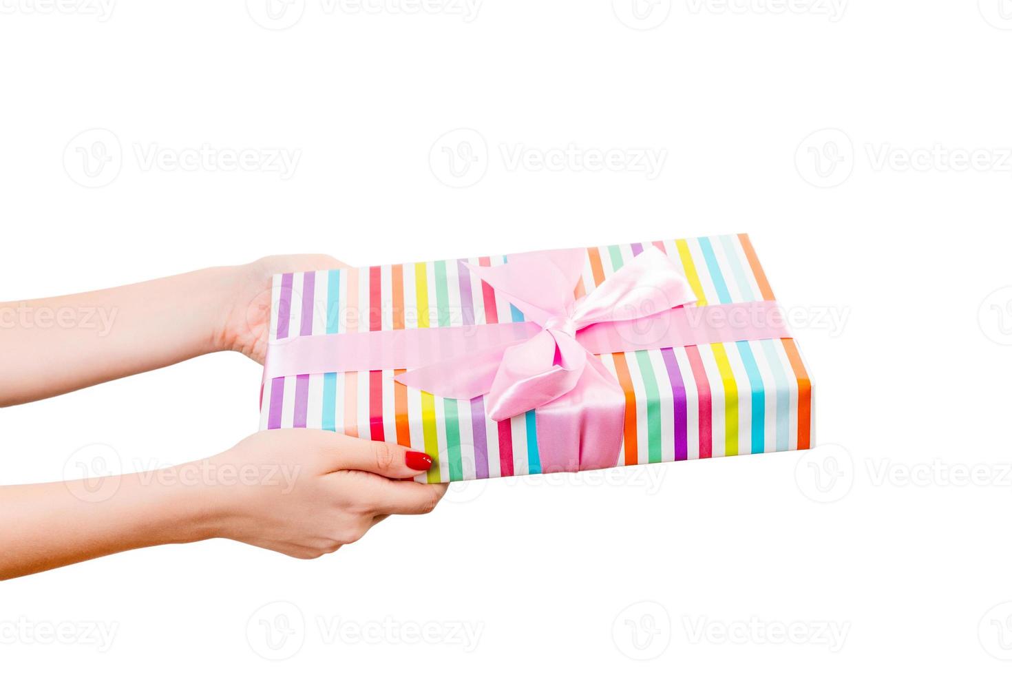 Woman hands give wrapped Christmas or other holiday handmade present in colored paper with pink ribbon. Isolated on white background, top view. thanksgiving Gift box concept photo