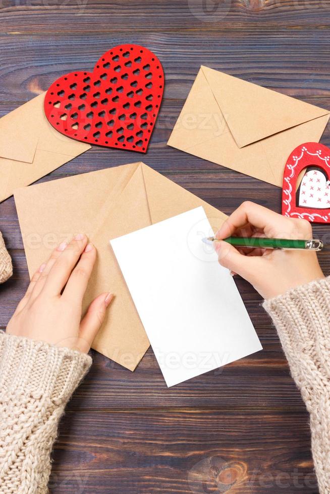 mujer escribiendo carta de amor o poema romántico para el día de san valentín, vista superior de manos femeninas. concepto de día de san valentín con copyspace foto