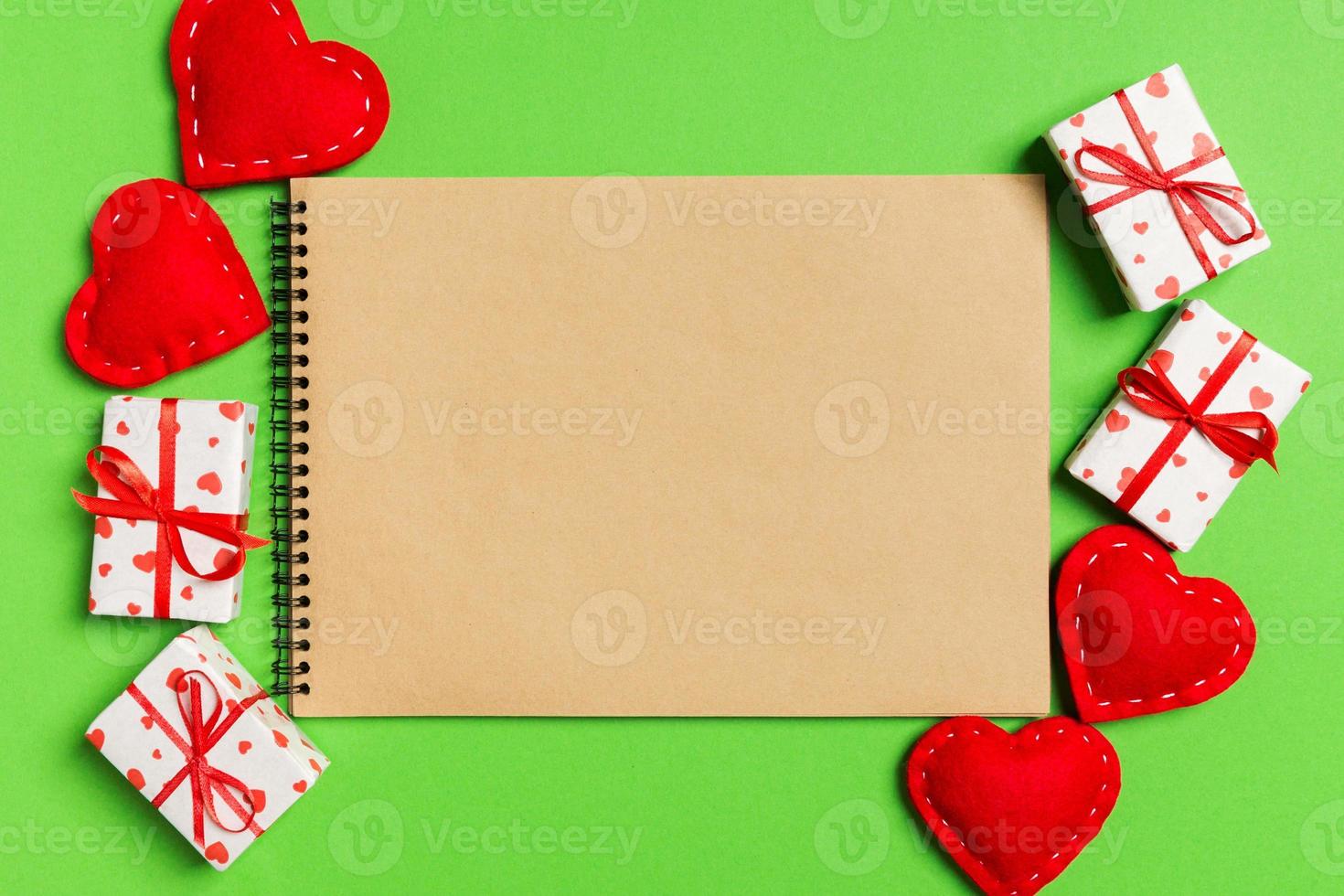 vista superior del cuaderno artesanal rodeado de cajas de regalo y corazones sobre fondo colorido. concepto del día de san valentín foto