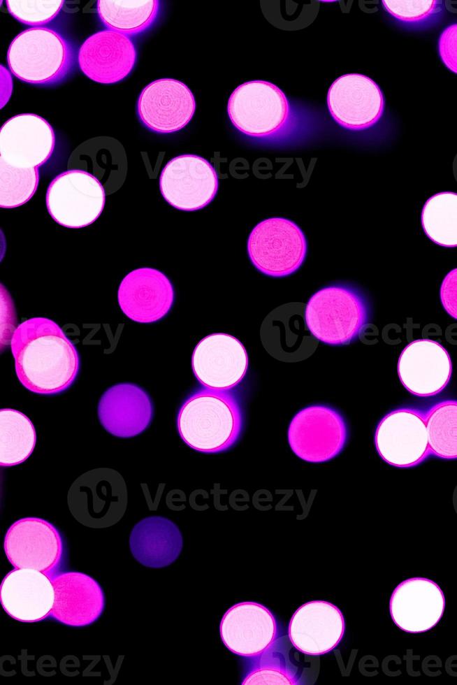 Unfocused abstract purple bokeh on black background. defocused and blurred many round light photo