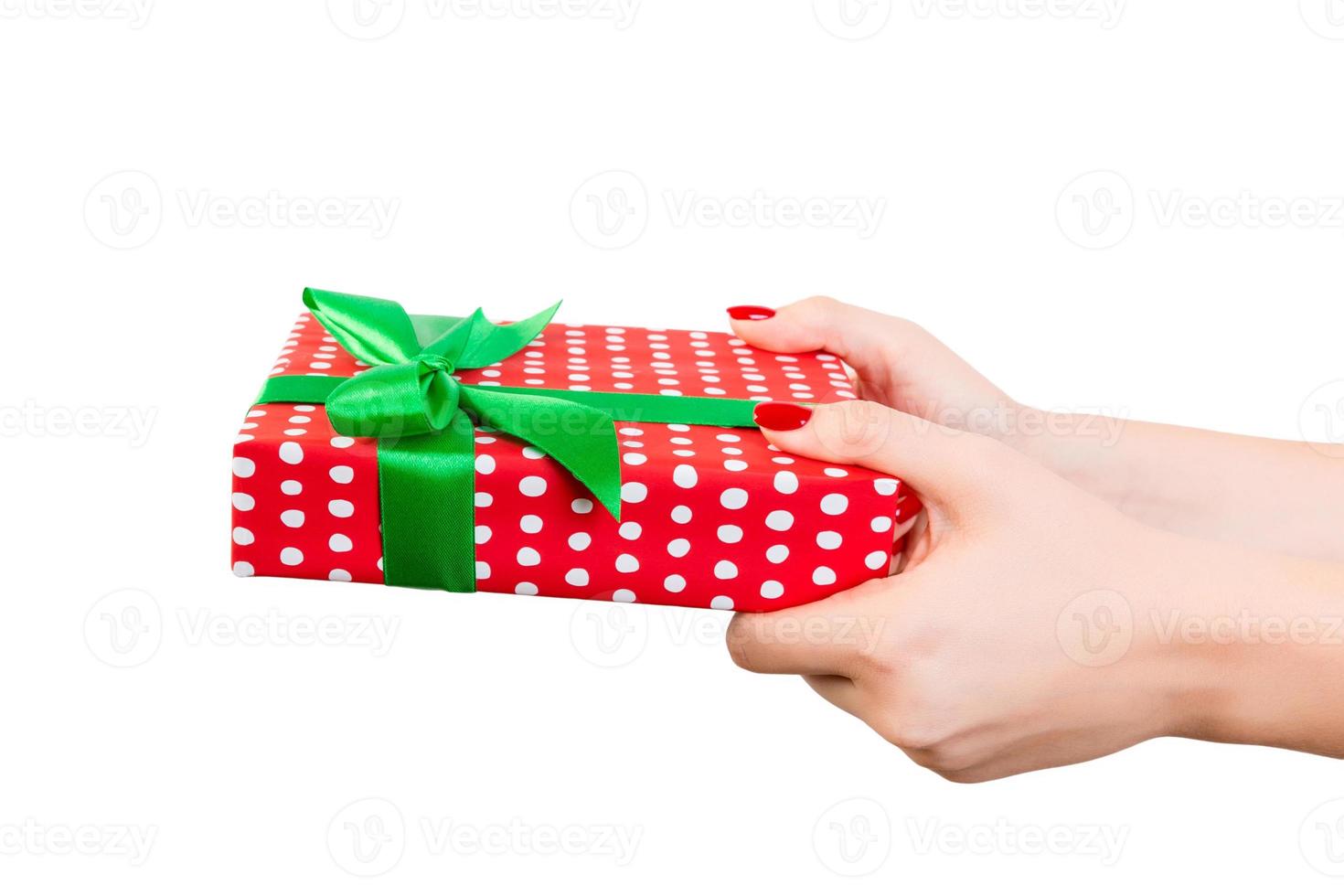Woman hands give wrapped Christmas or other holiday handmade present in red paper with Green ribbon. Isolated on white background, top view. thanksgiving Gift box concept photo