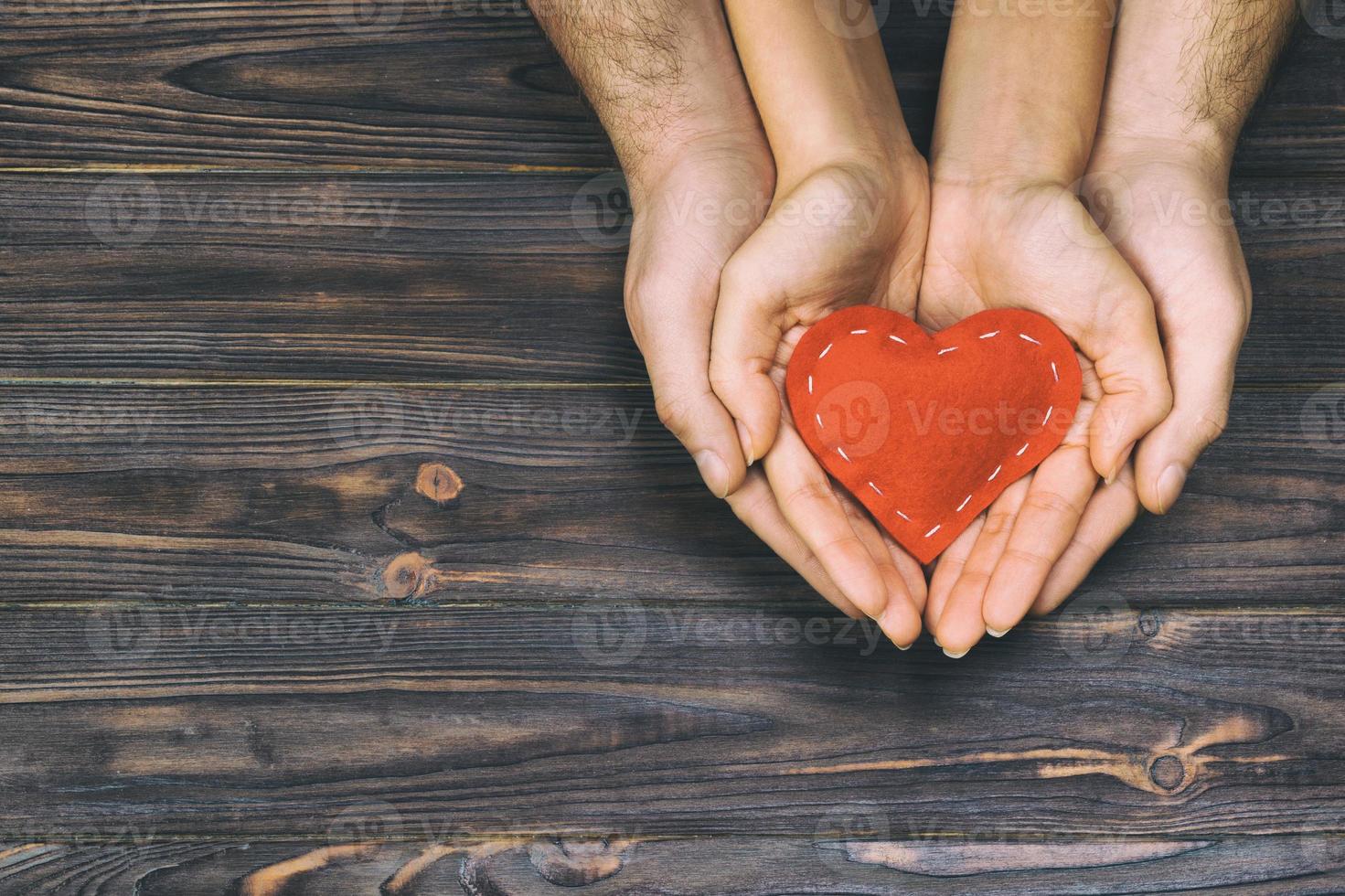 Love, family concept. Close up of man and woman hands holding red rubber heart together toned, vintage photo