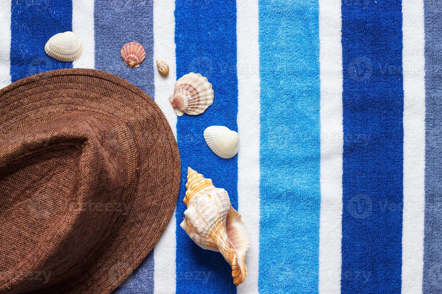 A summer holiday composition on a beach towel with seashells and a hat. photo