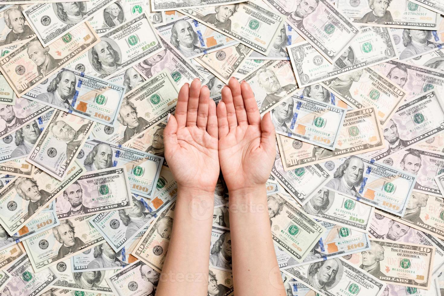 Top view of female hands on various dollar background. Wealth concept with empty space for your design. Begging money concept photo