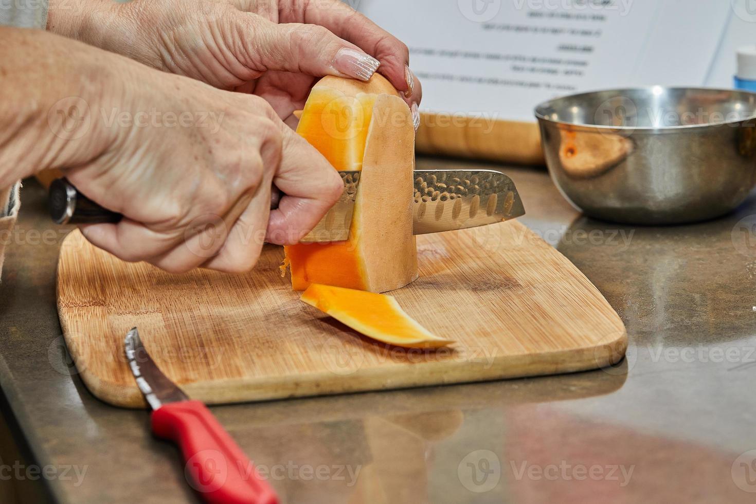Chef cuts pumpkin in the shape of pear on wooden board in the home kitchen photo