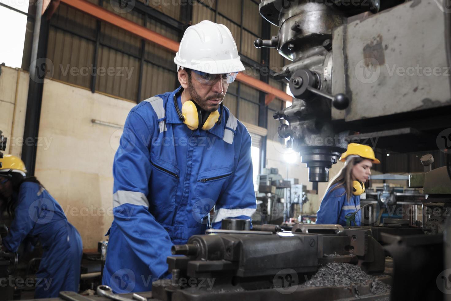 An industrial worker in protective safety uniform and hardhat, a Professional Caucasian male engineer works with metalwork machines in lathe manufacturing factory, mechanical production occupation. photo