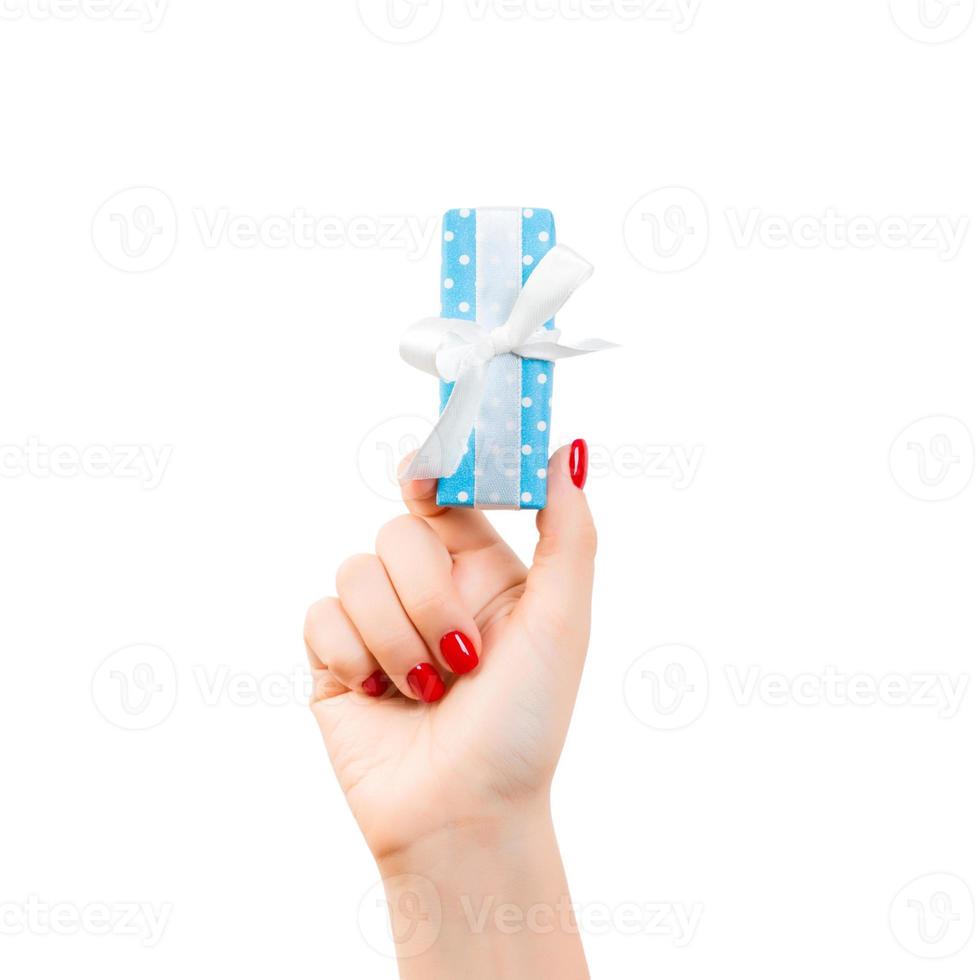 Woman hands give wrapped Christmas or other holiday handmade present in blue paper with white ribbon. Isolated on white background, top view. thanksgiving Gift box concept photo