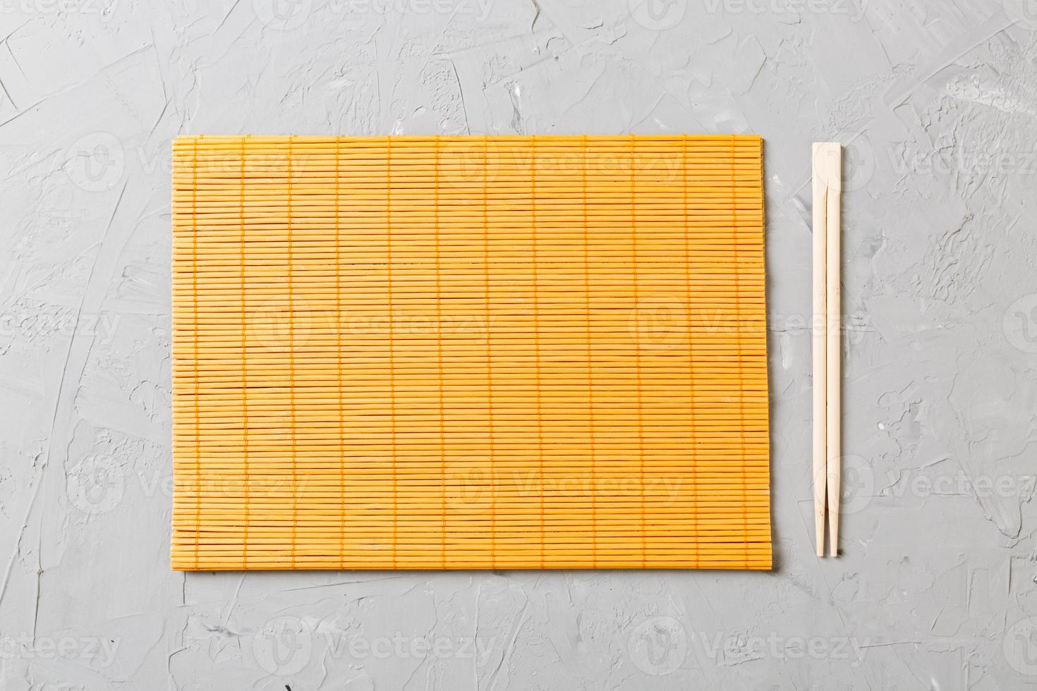 two sushi chopsticks with empty bamboo mat or wood plate on stone Background Top view with copy stace photo