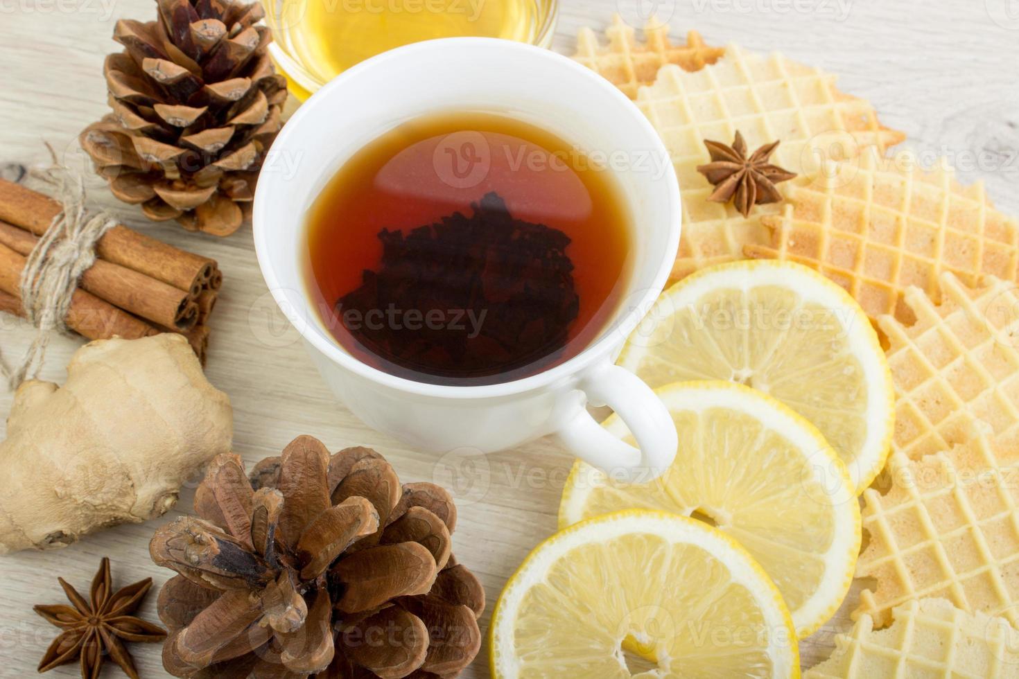 Cup of tea with honey, pinecone, badian, ginger, waffles and cinnamon photo