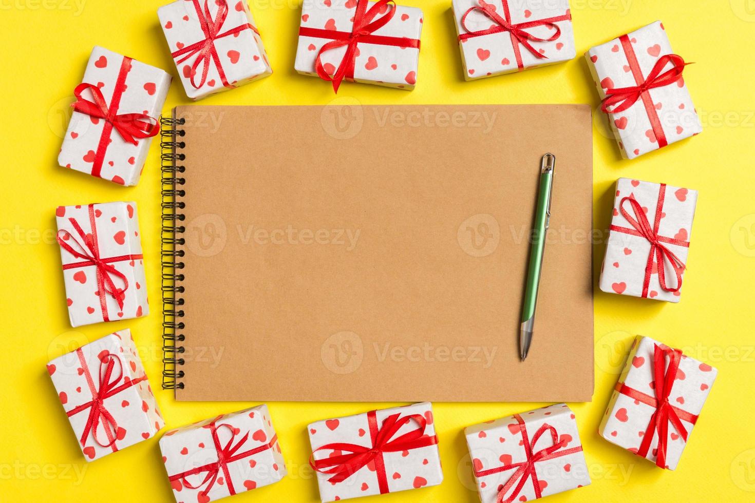 Top view of notebook surrounded with gift boxes on colorful background. Valentine's Day concept photo