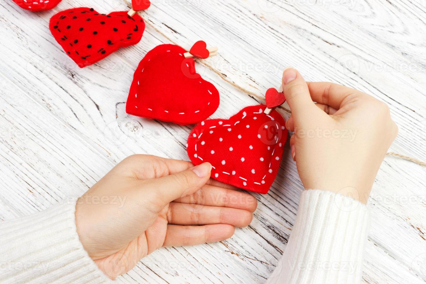 fondo de san valentín con almohada cosida diy corazones hechos a mano en manos de mujer en tablones de madera rústica. feliz dia de los enamorados, copia espacio foto