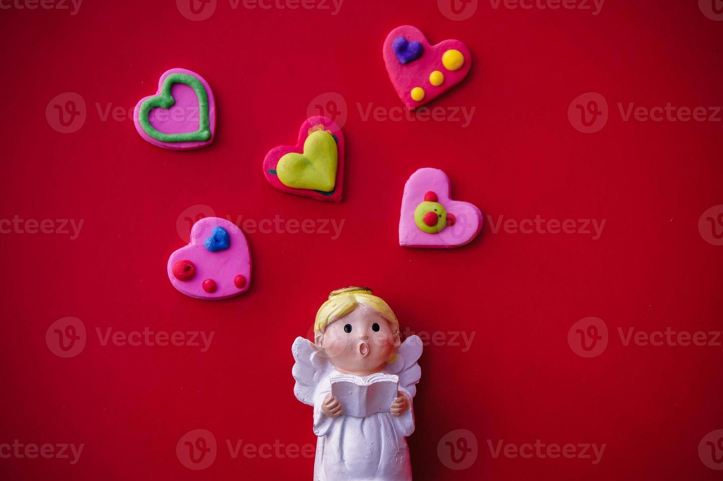 Cupid doll and heart-shaped on red background photo