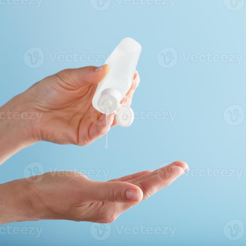 A bottle of Disinfectant gel in your hands on a blue background. Antiseptic treatment of hands from bacteria Sanitizer. photo