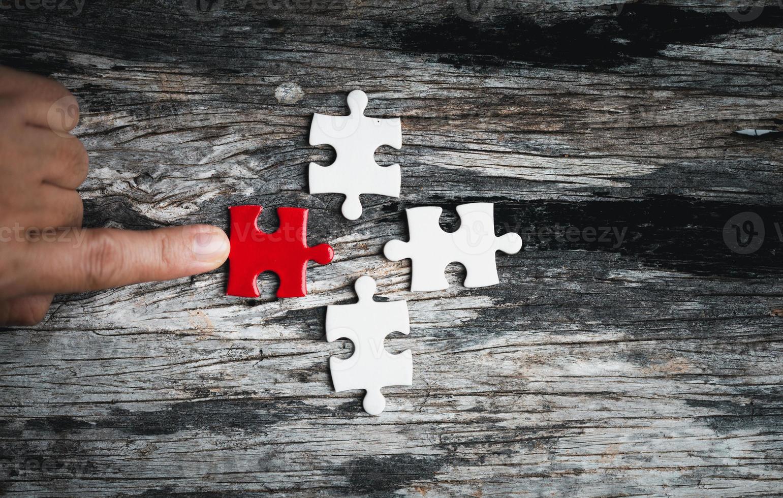 Pieces of jigsaw puzzle in woman's hands. White details of jigsaw puzzle piece on wooden background. Concept of working together as a business team. The idea of getting involved, working for success. photo