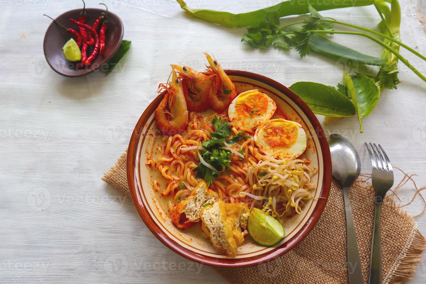 laksa, laksa curry made from vermicelli, noodles, bean sprouts, egg, tofu lime, and shrimp with a spicy soup sauce that is rich in spices. laksa served on bowl, isolated on white background. photo