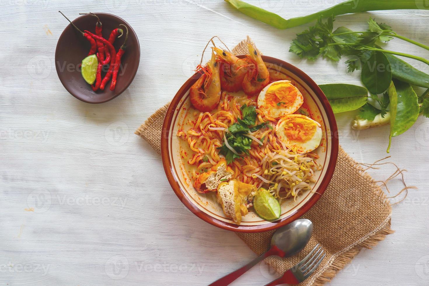 laksa, curry laksa elaborado con fideos, fideos, brotes de soja, huevo, tofu, lima y camarones con una salsa de sopa picante rica en especias. laksa servido en tazón, aislado sobre fondo blanco. foto