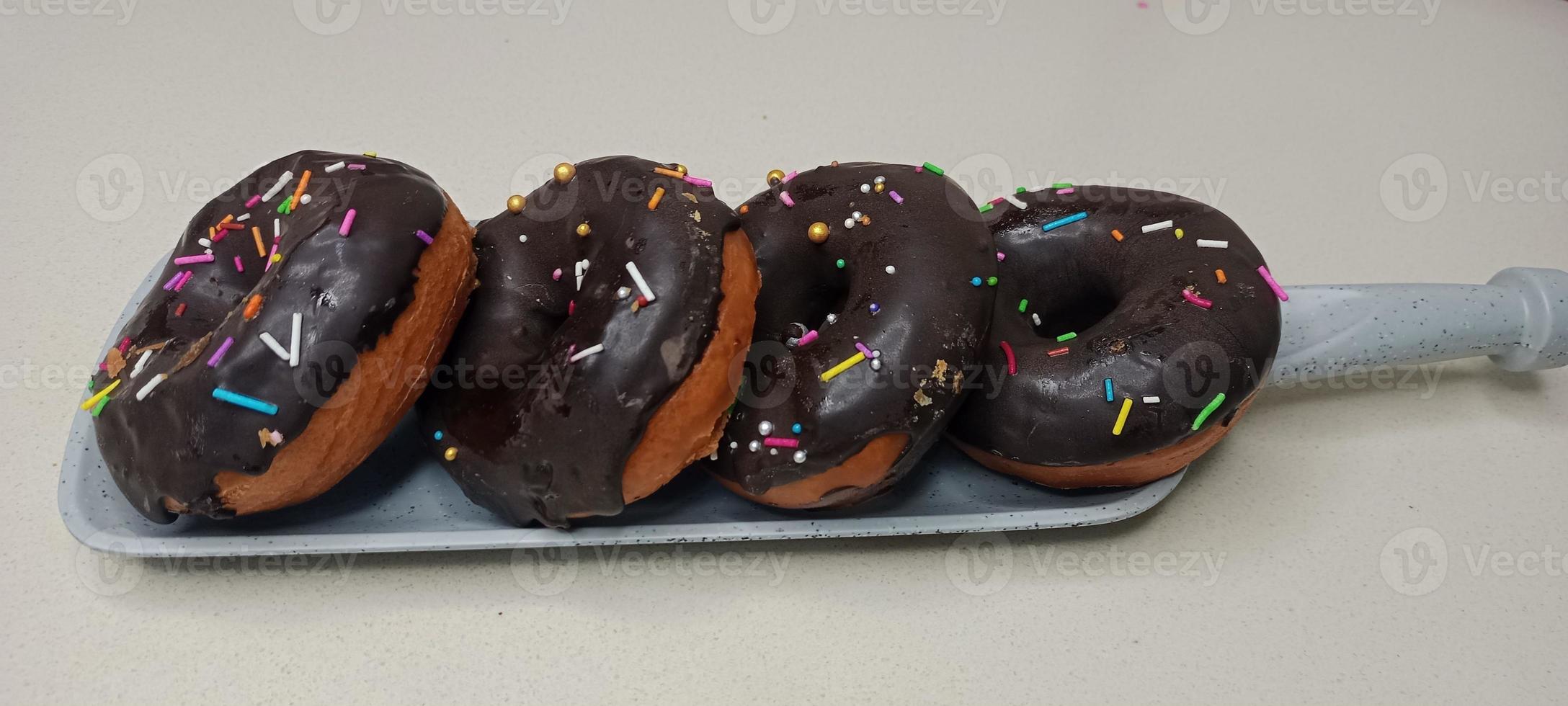 assorted donuts with chocolate frosted, pink glazed and sprinkles donuts. Donuts in hand or tray photo