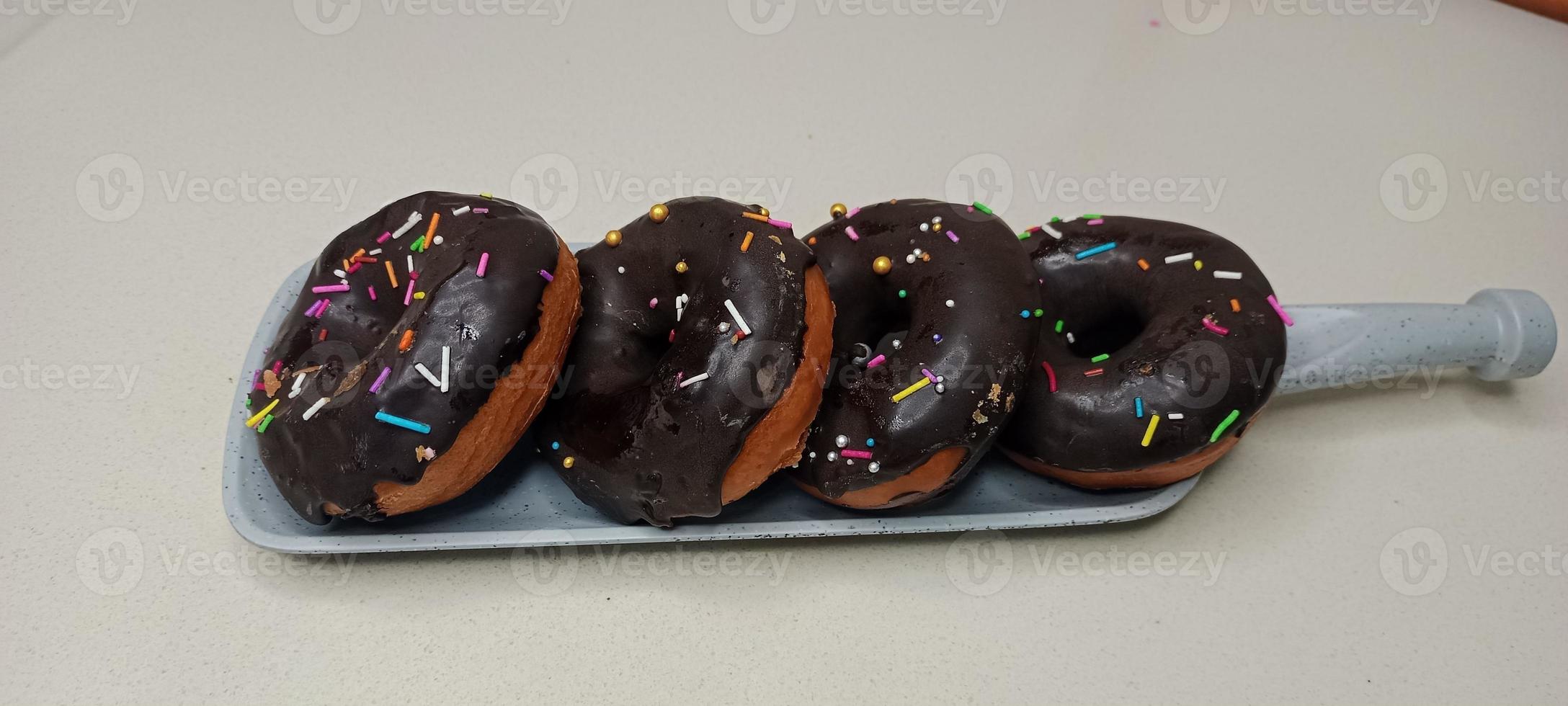 assorted donuts with chocolate frosted, pink glazed and sprinkles donuts. Donuts in hand or tray photo