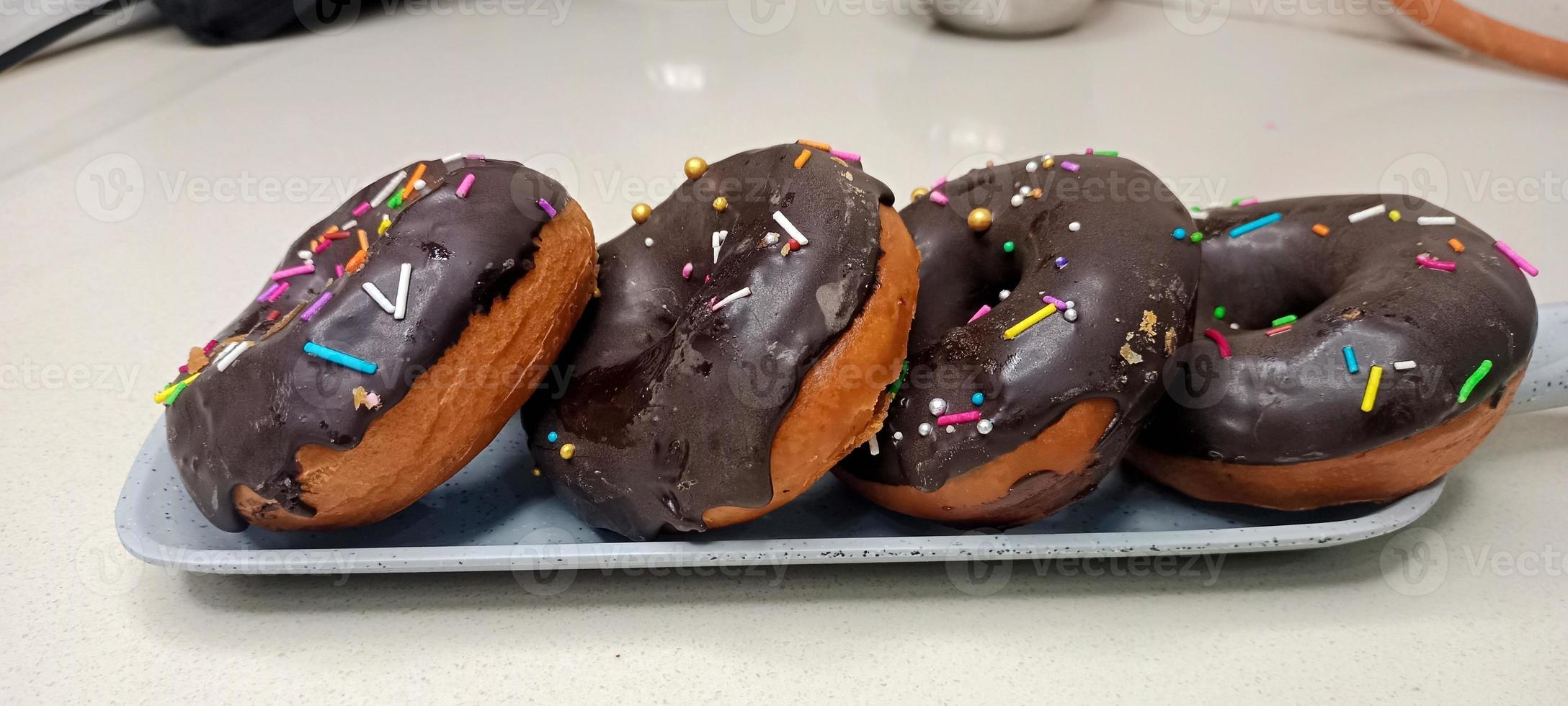 rosquillas variadas con glaseado de chocolate, glaseado rosa y rosquillas. donas en mano o bandeja foto