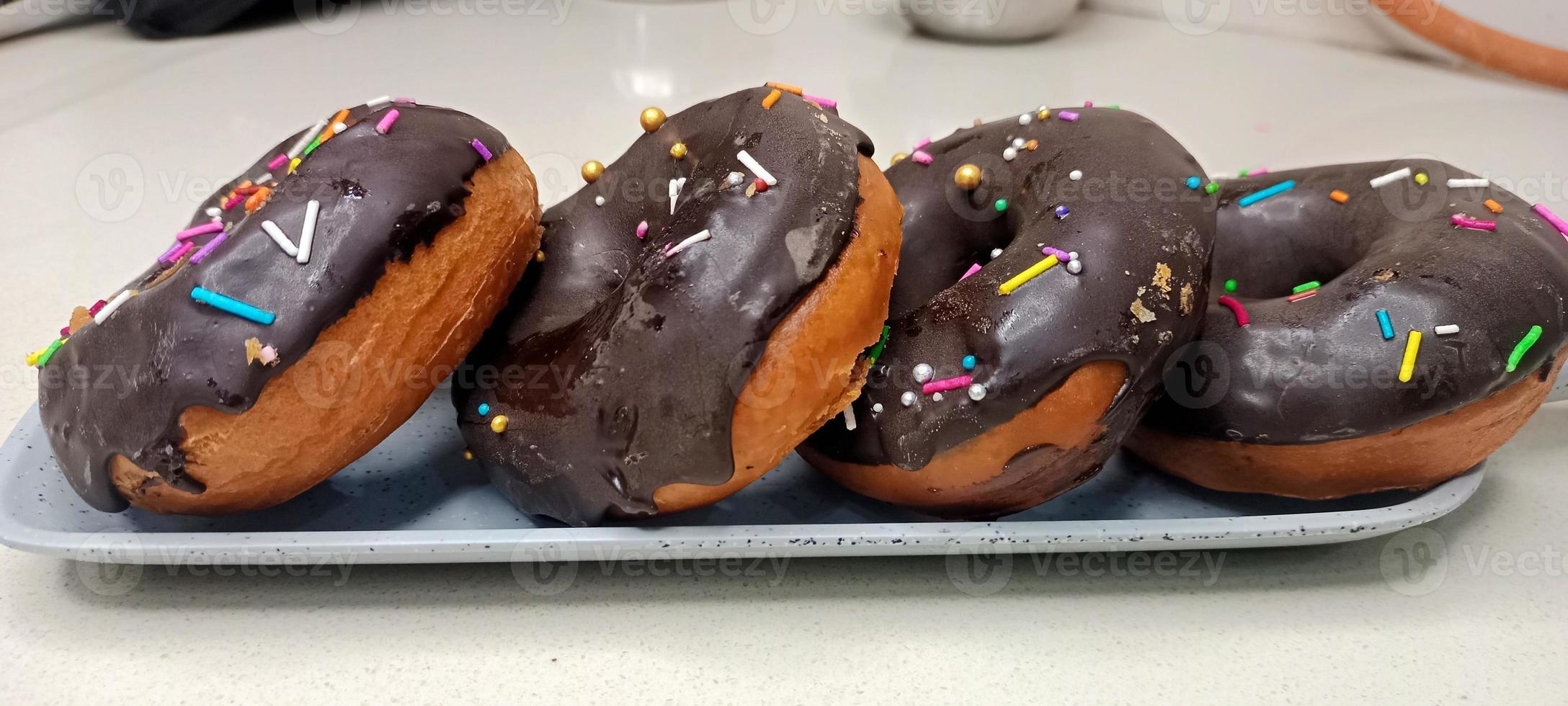 assorted donuts with chocolate frosted, pink glazed and sprinkles donuts. Donuts in hand or tray photo