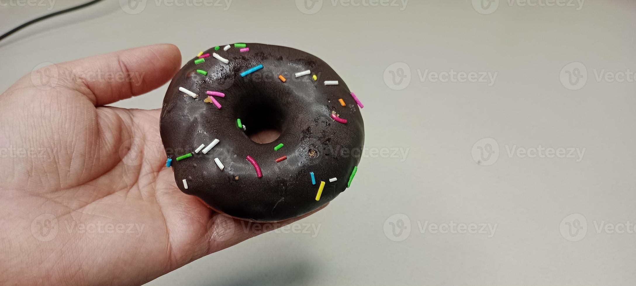 assorted donuts with chocolate frosted, pink glazed and sprinkles donuts. Donuts in hand or tray photo