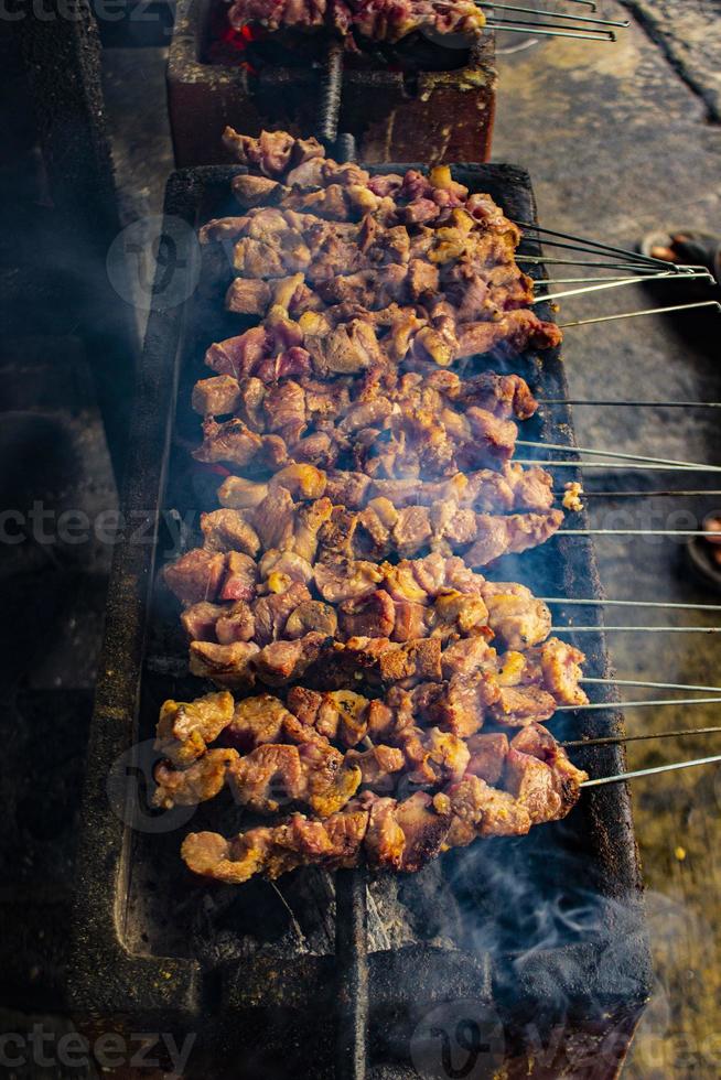 sate klatak o sate kambing o satay de cabra, cordero, cordero o carne de cabra satay con ingrediente de carbón en fuego rojo asado por personas, indonesia cocinando satay. con enfoque selectivo foto