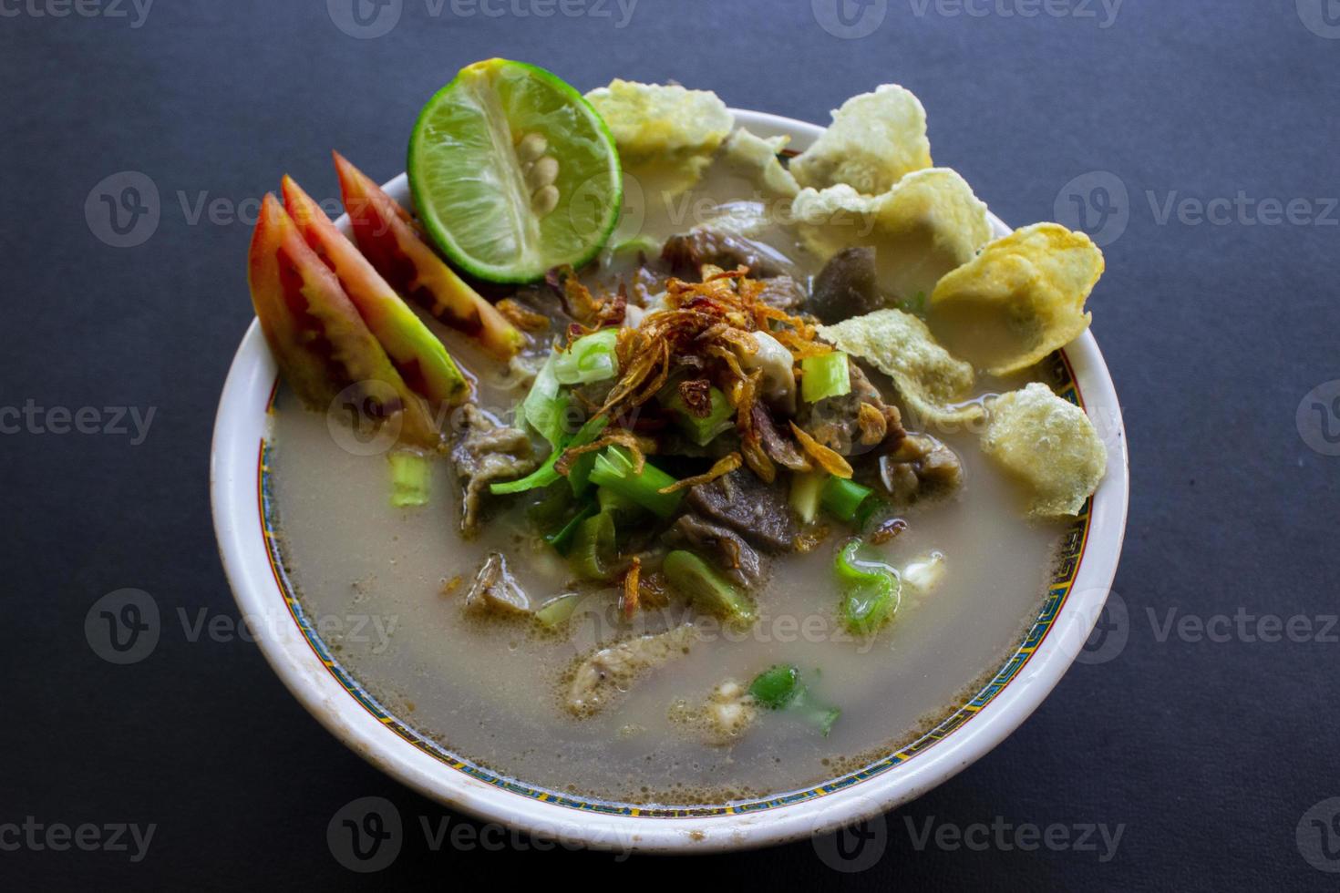 sop kaki kambing a traditional food from Betawi, Jakarta Indonesia, made from mutton or lamb, offal, spices. isolated on black background.This food is like lamb stew on black background photo