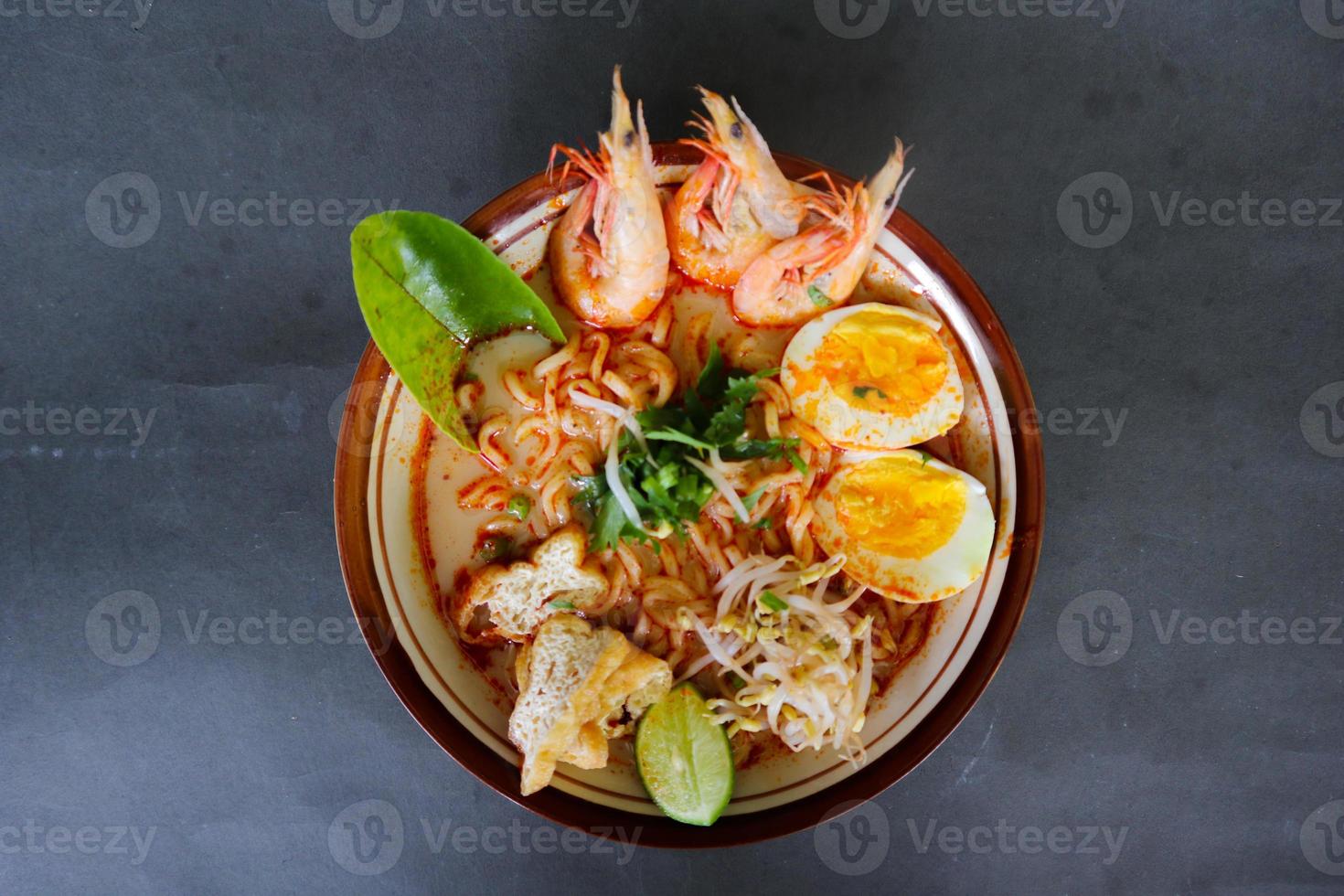 laksa, laksa curry made from vermicelli, noodles, bean sprouts, egg, tofu lime, and shrimp with a spicy soup sauce that is rich in spices. laksa served on bowl, isolated on white background. photo
