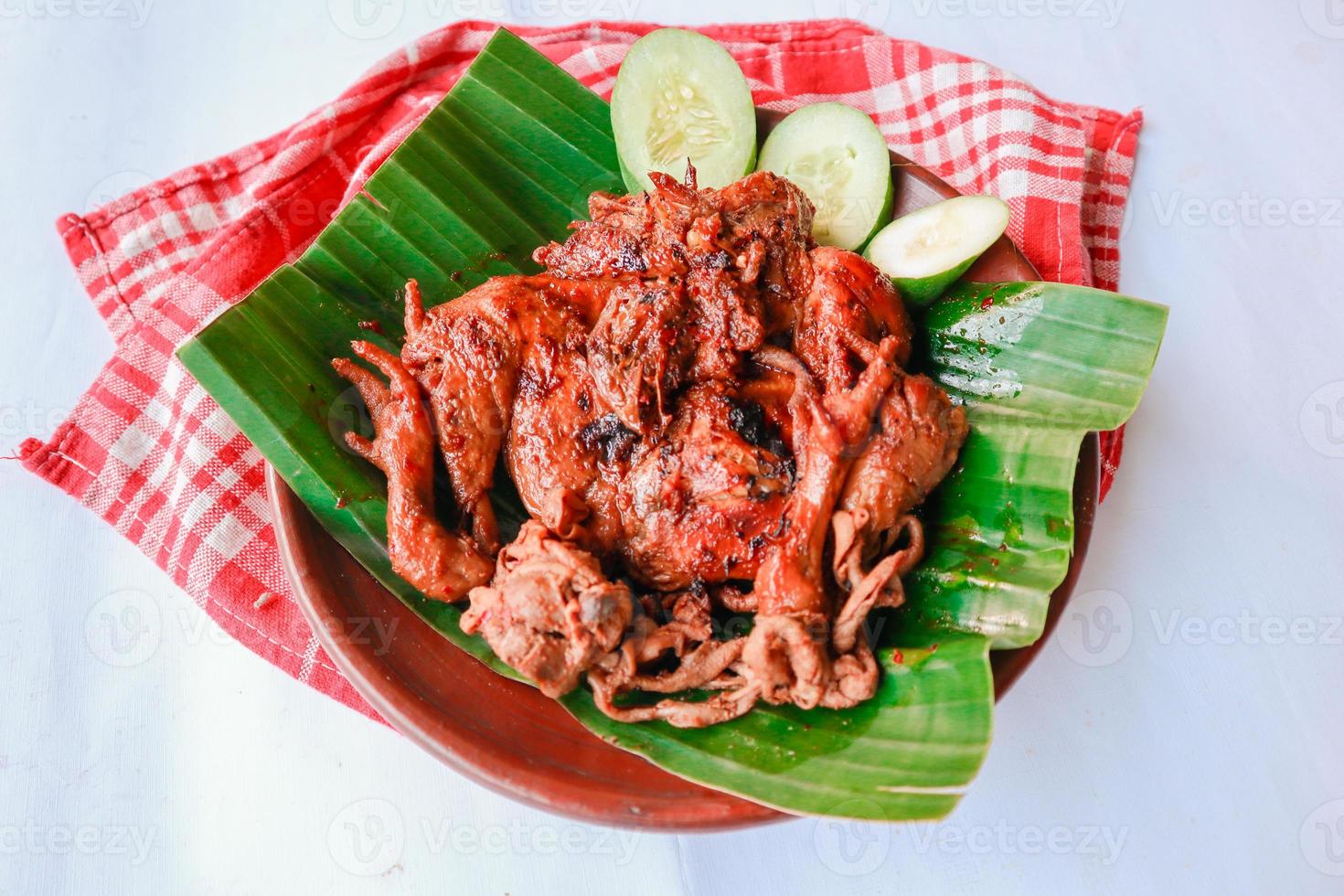 grilled chicken or ayam bakar with cucumber slash served on banana leaf and plate. ayam bakar is traditional grilled chicken from indonesia photo